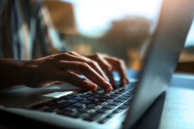 Hands typing on a laptop keyboard.