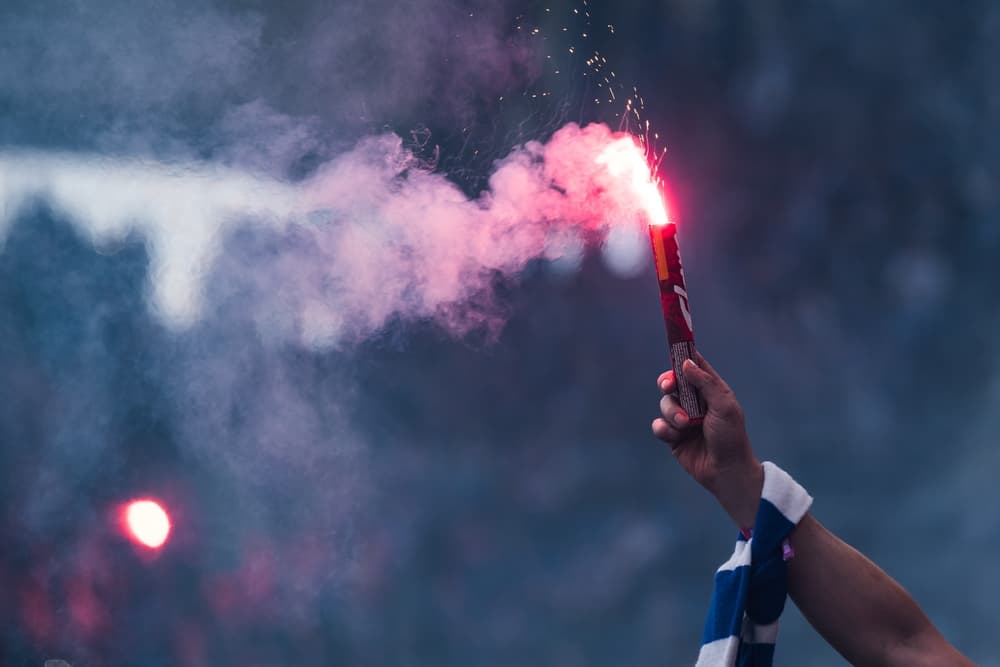 Image of flare held in the hand of a soccer fan.
