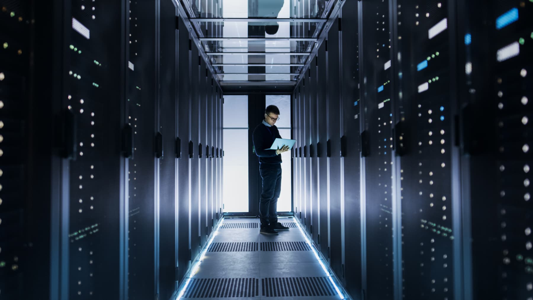 Man with laptop standing in hallway.