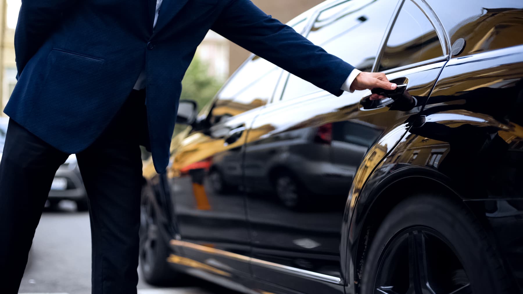 Driver opening rear door of car.