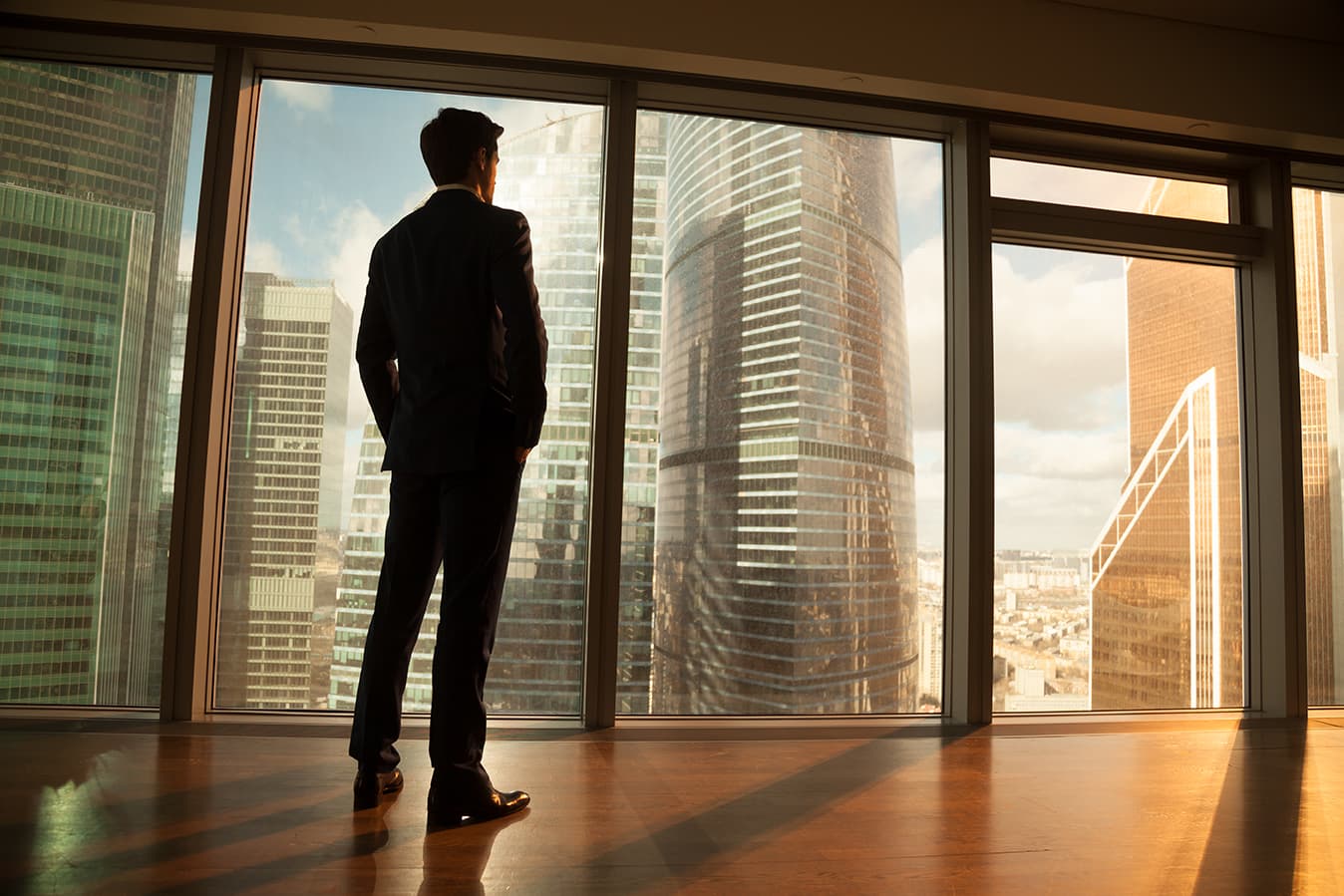 contemplative businessman looking out window on cityscape