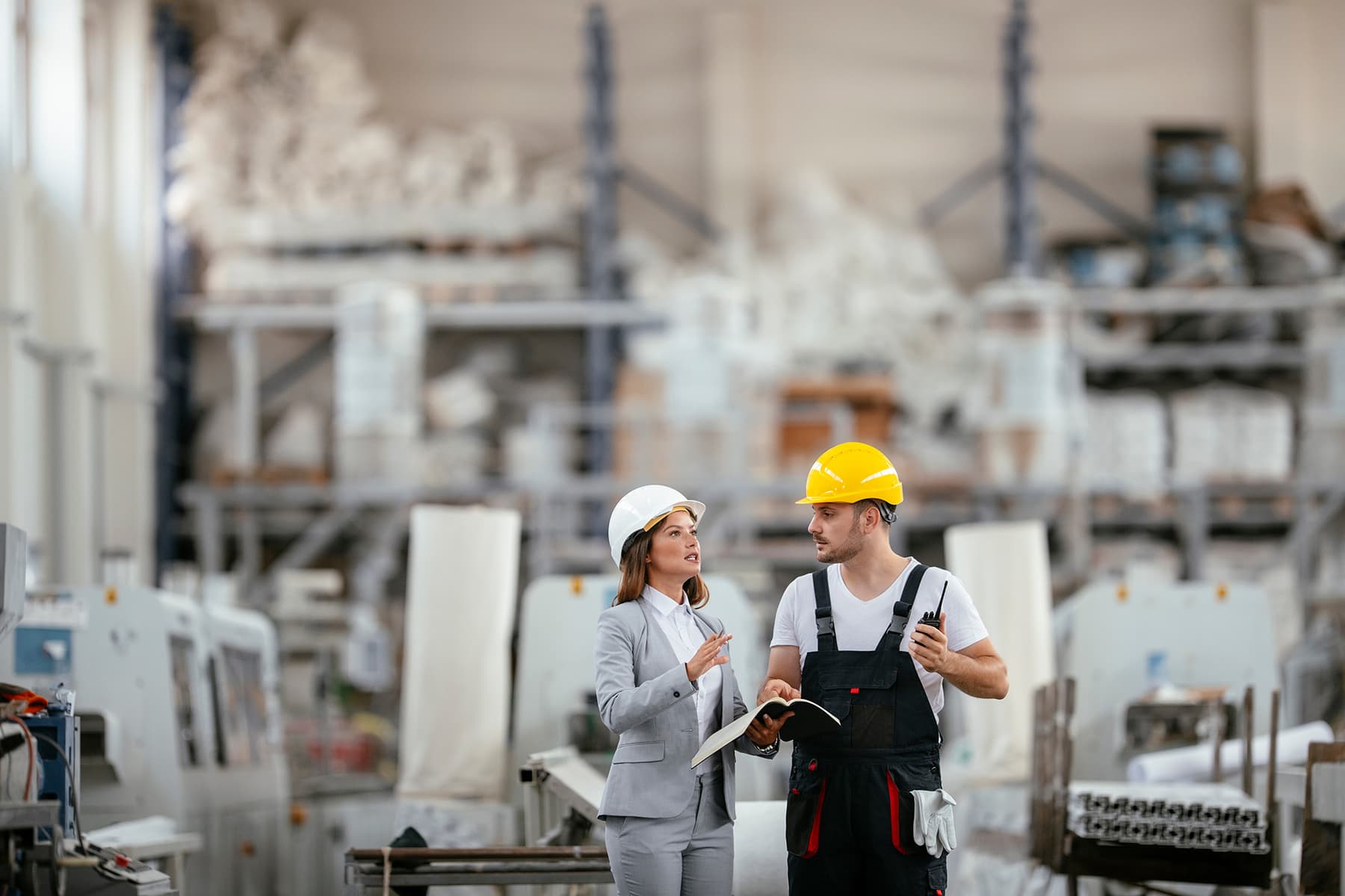 Manager talking to employee wearing hardhats in a warehouse