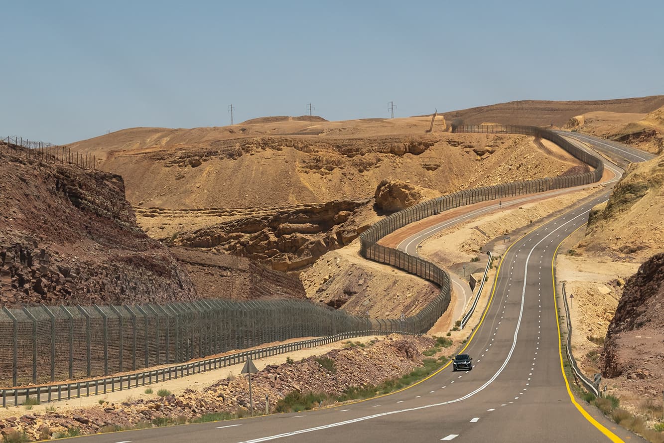 Highway through the Negev Desert on the border with Egypt showing the fence between the countries in Southern Israel