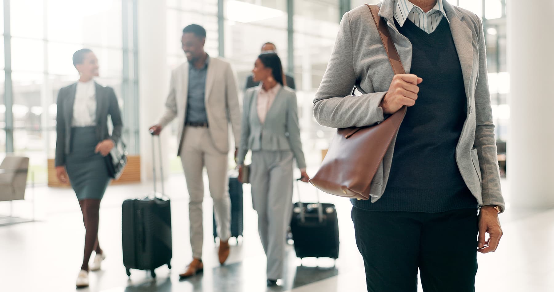business travelers with carryon luggage walking thru well lit airport
