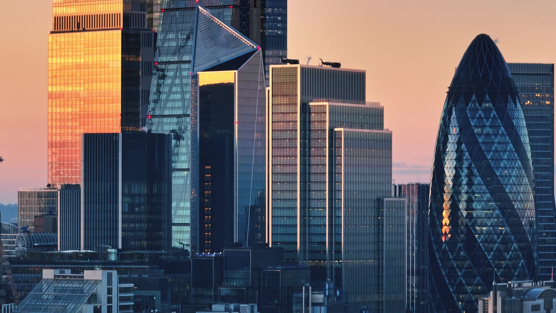 Modern glass skyscrapers reflecting sunset light during golden hour in London's financial district