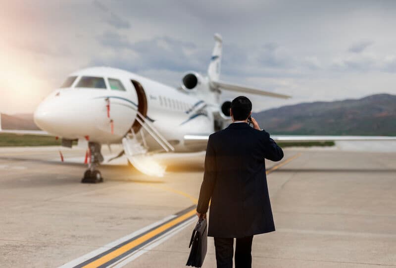 wealthy business man on the phone walking towards a private jet on the runway