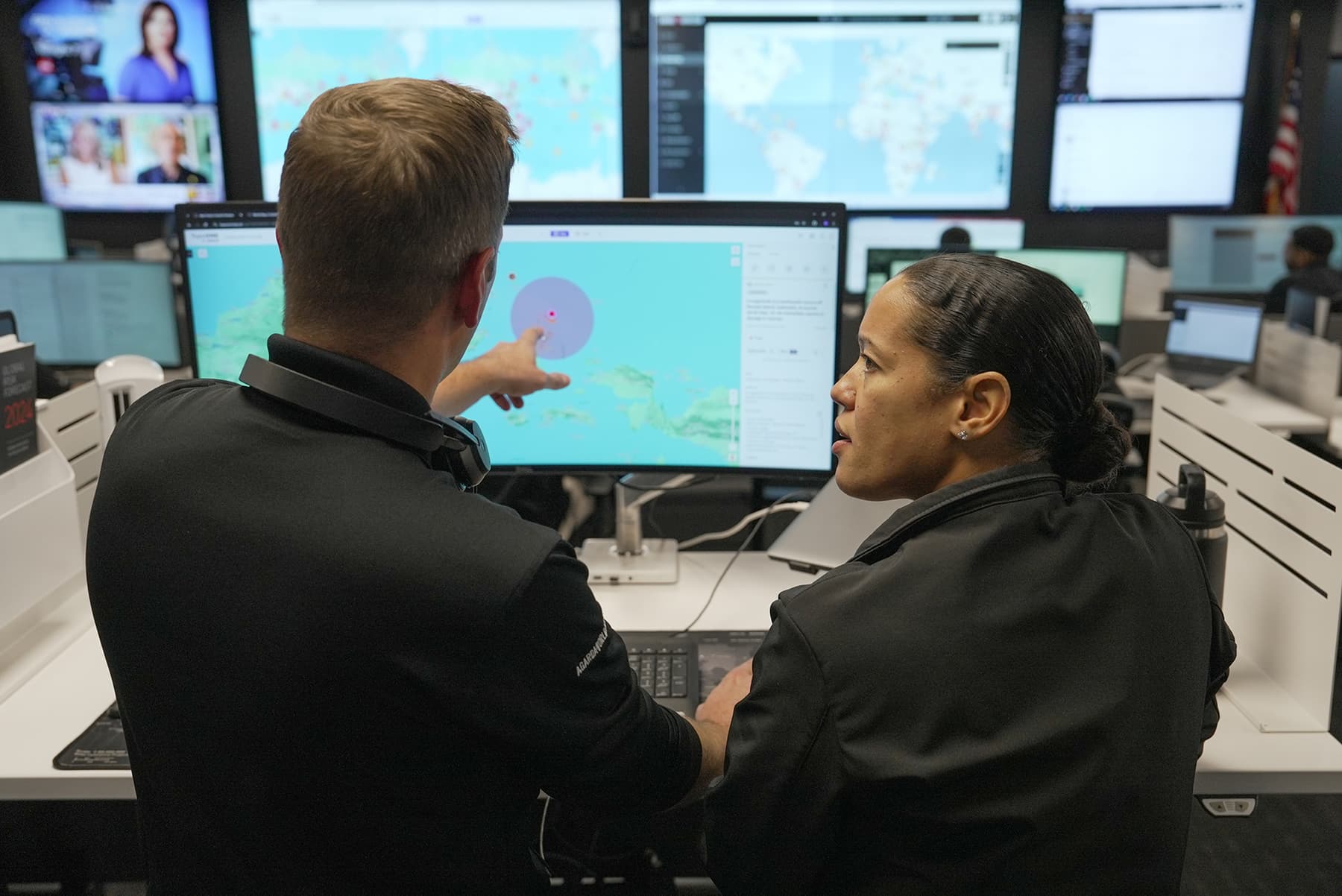 two analysts discussing data on shared computer screen in a security operations center two analysts discussing data on shared computer screen in a security operations center